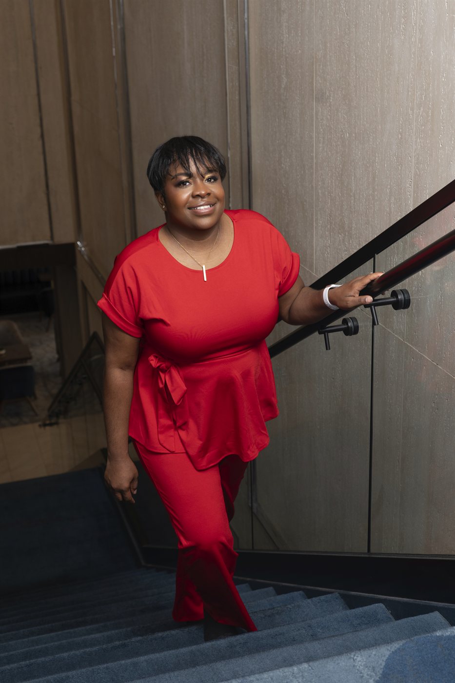 Shavonda Lawson smiling on a staircase, one hand resting on the railing